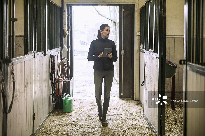 中年妇女在马厩中使用平板电脑图片素材