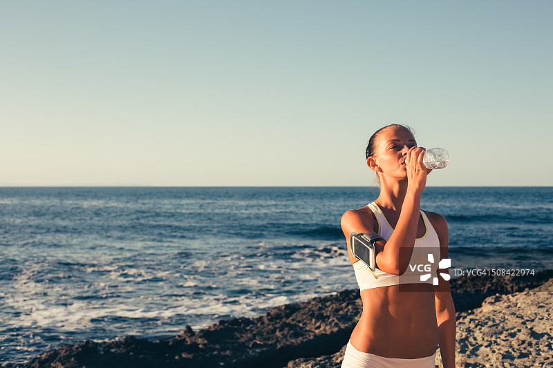 女运动员在海滩喝水图片素材