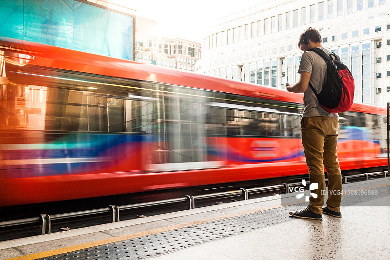 年轻男人背着背包戴着耳机等火车图片素材