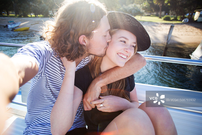 年轻情侣在船上自拍亲吻（阳光 flare）图片素材