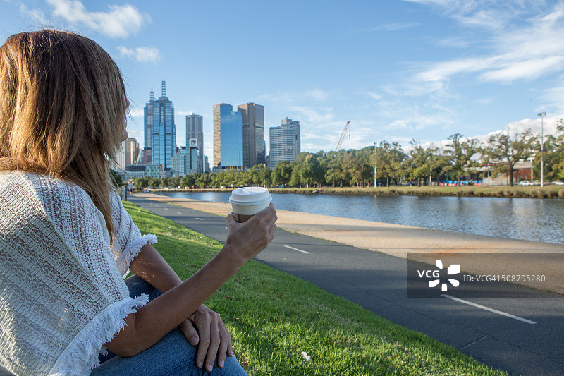 在墨尔本亚拉河畔眺望市区的年轻女子图片素材