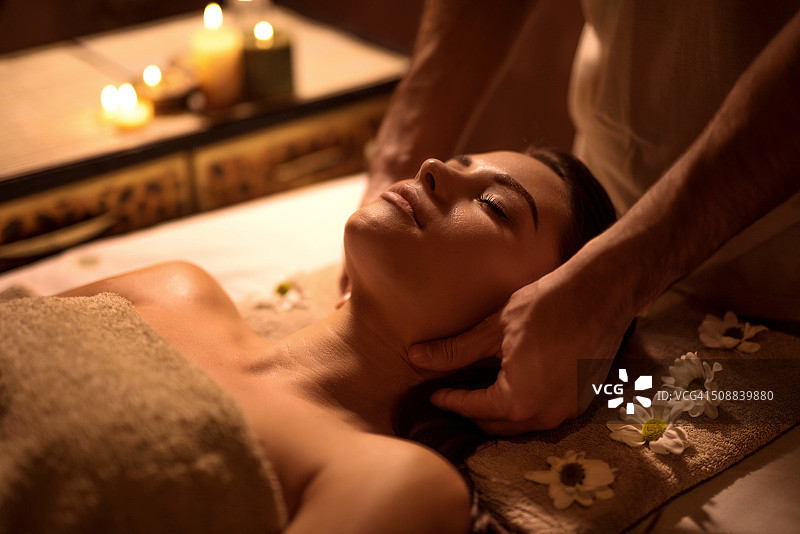 年轻女人在水疗中心享受头部按摩图片素材