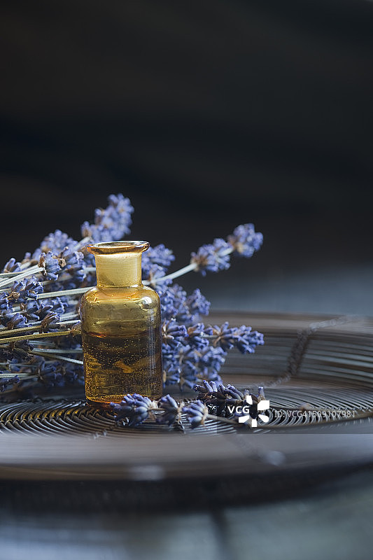 玻璃瓶薰衣草精油与狭叶薰衣草枝条图片素材