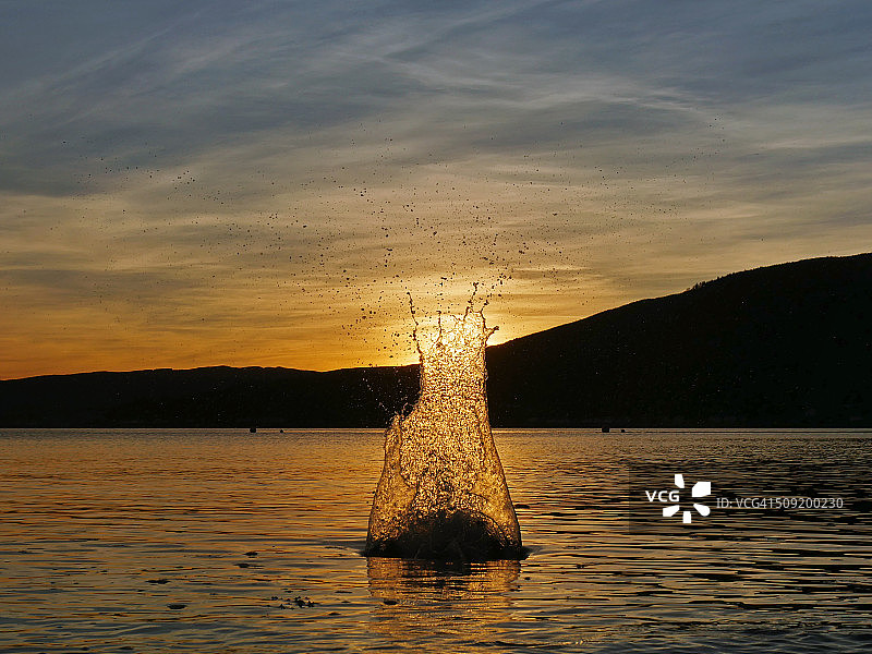 夕阳下，扁平石块扔入苏格兰朗湖的水花图片素材