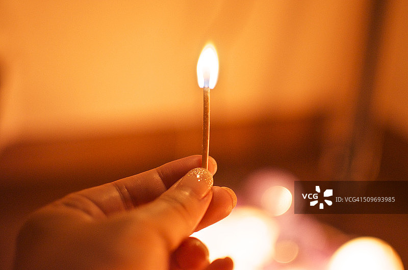 女人在房间里拿着一根点燃的火柴图片素材