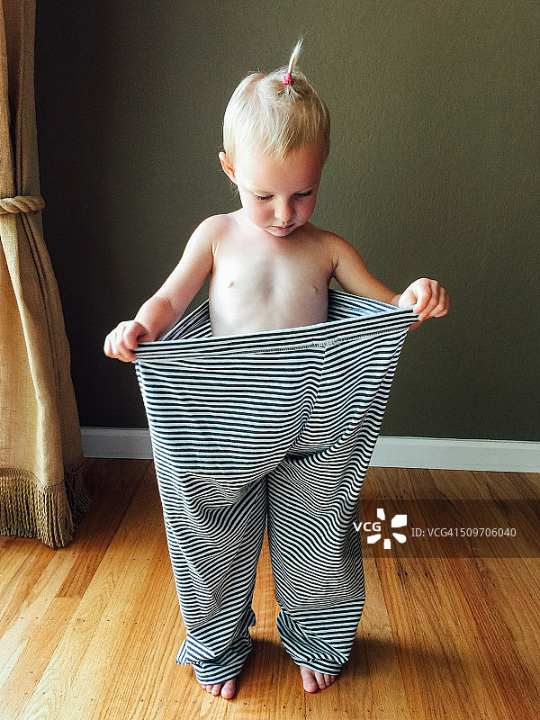 穿着妈妈肥大睡裤的可爱幼儿女孩图片素材