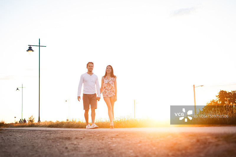 相爱年轻情侣在公园牵手散步图片素材