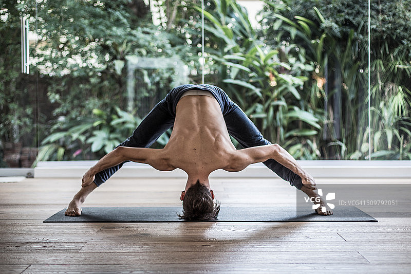 男人做Prasarita Padottanasana式瑜伽图片素材