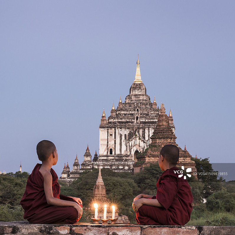 坐在寺庙顶上的年轻佛教僧侣图片素材