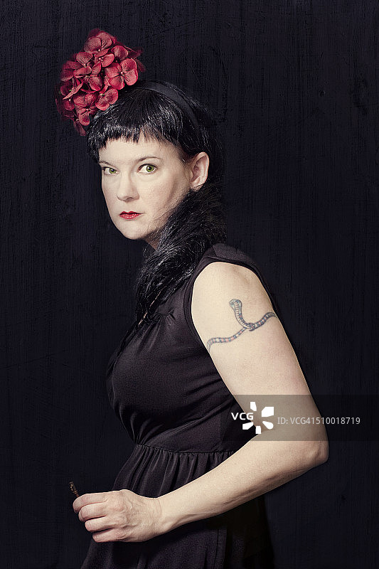 有蛇纹身和红色花朵发饰的女人图片素材