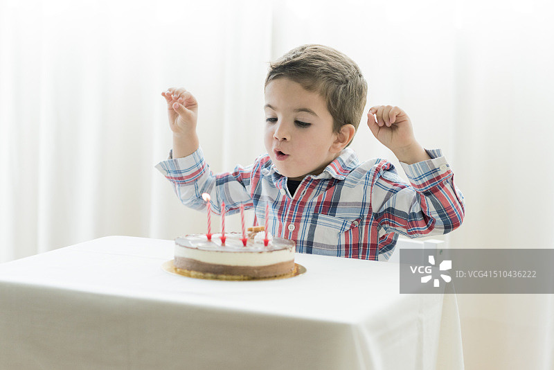 小男孩吹灭生日蛋糕上的蜡烛图片素材