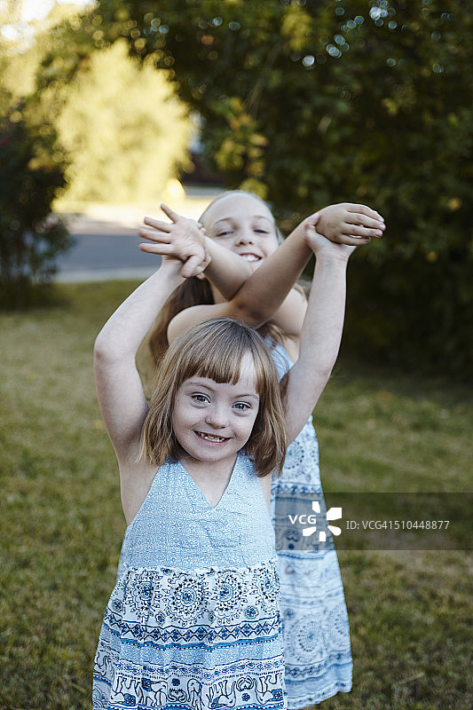 穿着蓝色连衣裙的姐妹在院子里玩耍图片素材