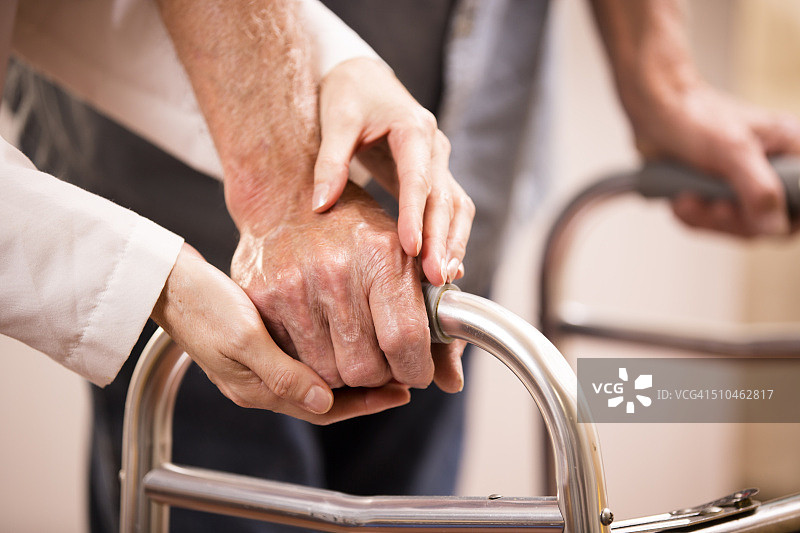 女医生帮助老年男性患者使用助行器，手部特写图片素材