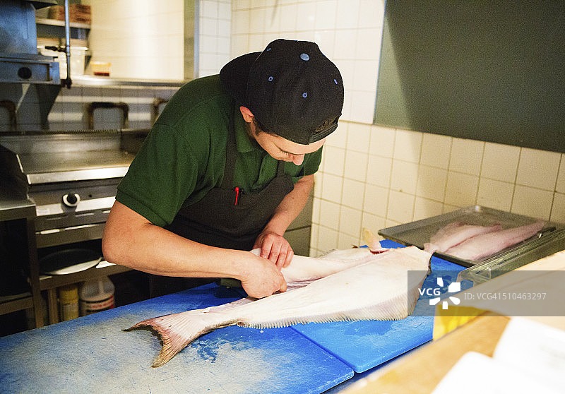厨师在餐厅厨房里给比目鱼剔骨横版图片素材