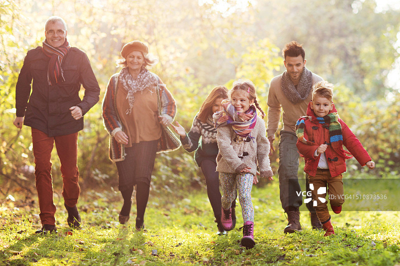 快乐的多代同堂家庭在公园里追逐玩耍图片素材