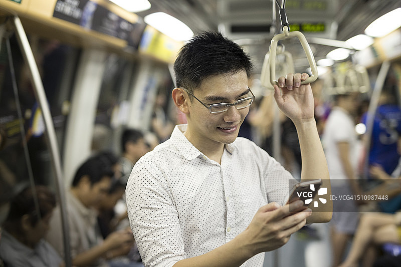 在地铁上使用智能手机的亚洲男人图片素材