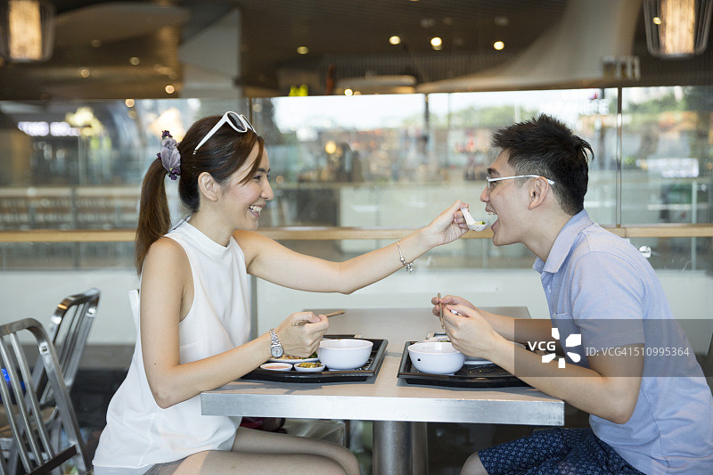 在美食广场共进午餐的亚洲男人和女人图片素材