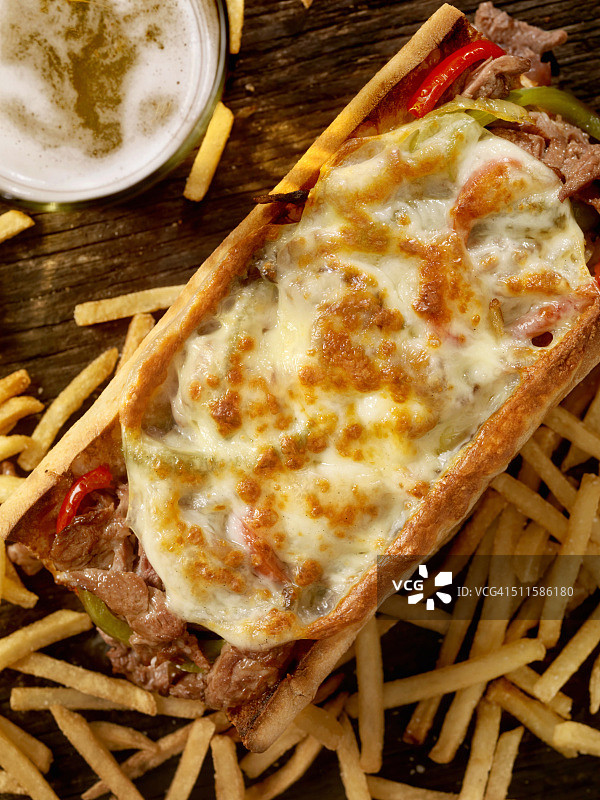 费城波萝伏洛干酪牛排三明治配薯条和啤酒图片素材