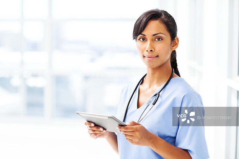 漂亮的医生在医院里拿着数位板图片素材