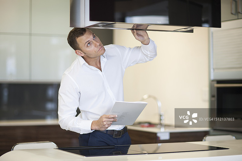 中年男人在厨房展厅检查抽油烟机图片素材