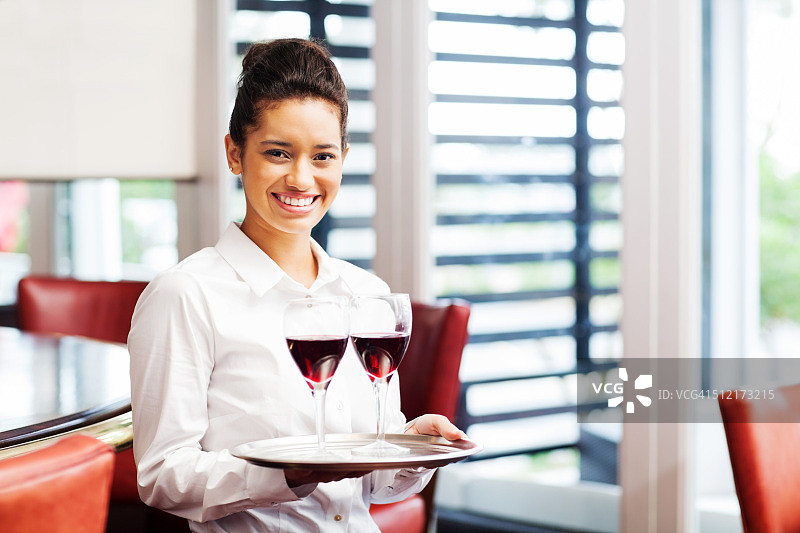 餐厅里手持红酒杯托盘的女服务员图片素材