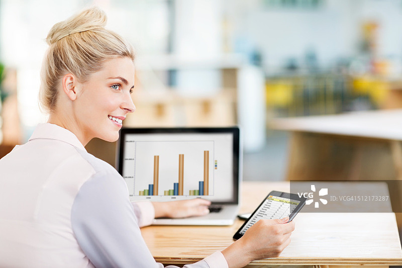 女企业家在办公桌前使用笔记本电脑和数位板图片素材