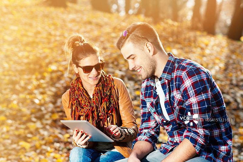 阳光明媚的日子里，情侣使用平板电脑图片素材