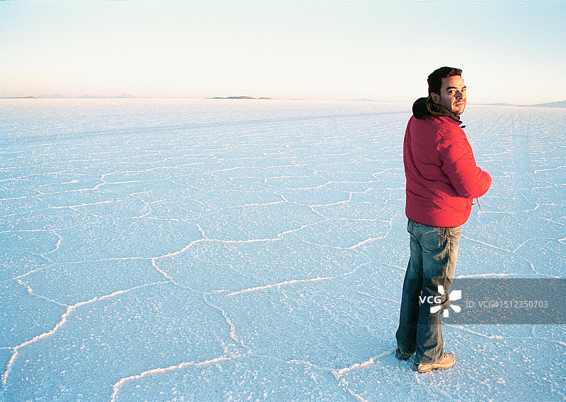 日出时站在乌尤尼盐沼的男人图片素材