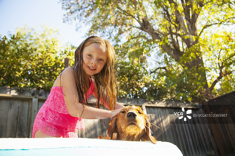 在花园泳池里抚摸小狗的女孩肖像图片素材