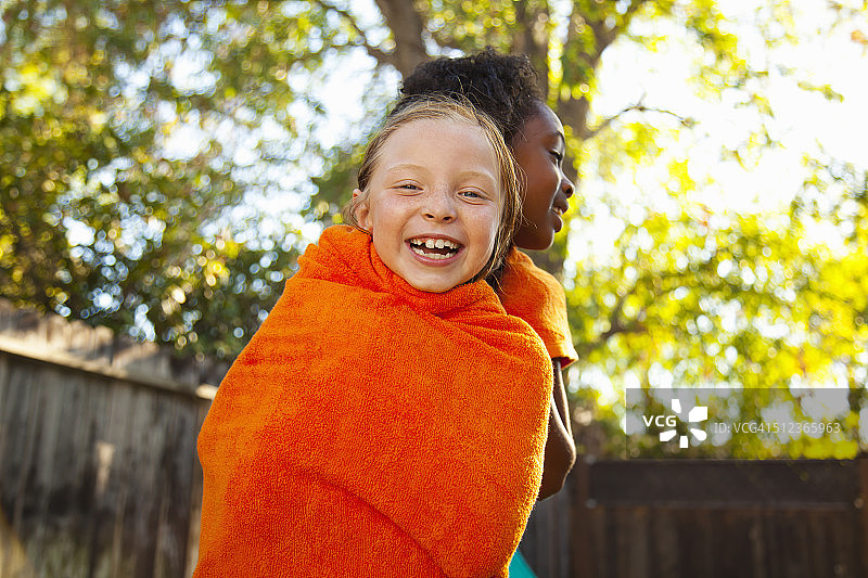 两个女孩在花园里裹着橙色毛巾图片素材