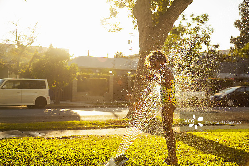 站在花园洒水器旁的女人图片素材