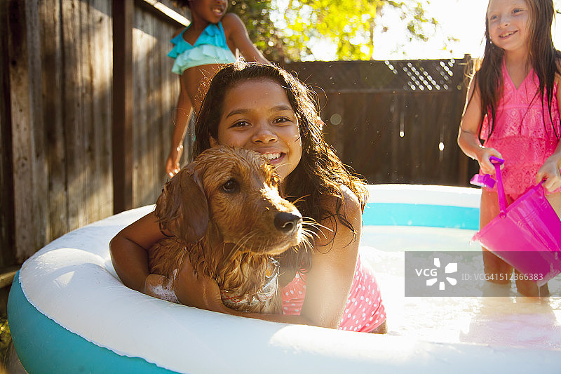 三个女孩和一条在花园水池里的狗图片素材