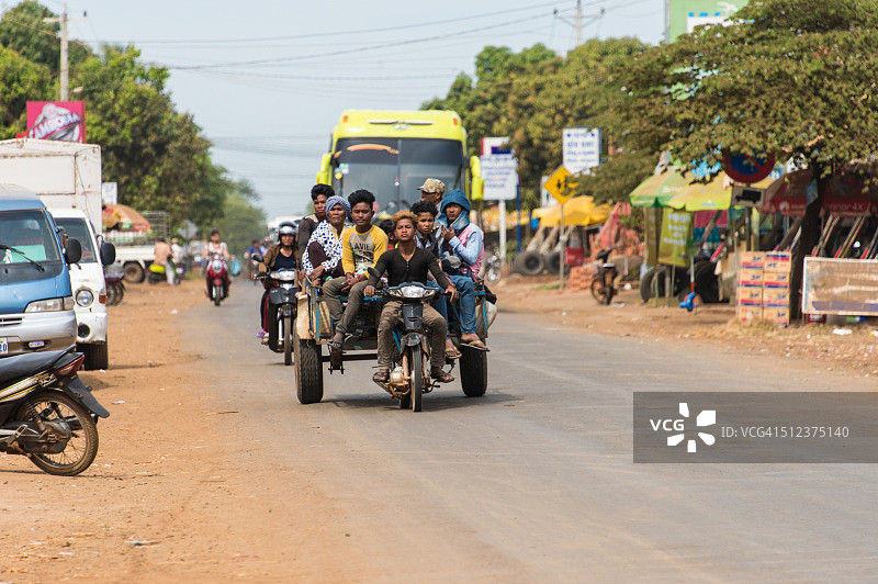 柬埔寨道路上常见的景象：载有多名乘客的轻便摩托车和拖车图片素材