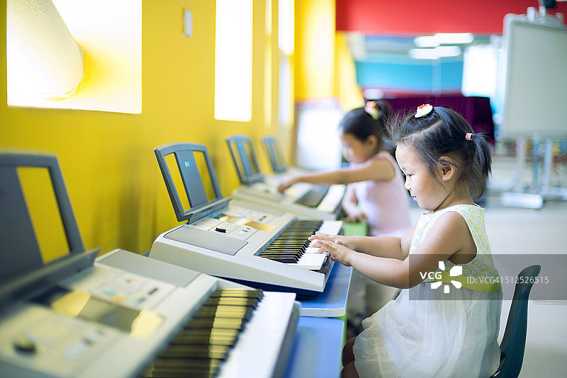 小女孩在幼儿园里弹电子琴图片素材