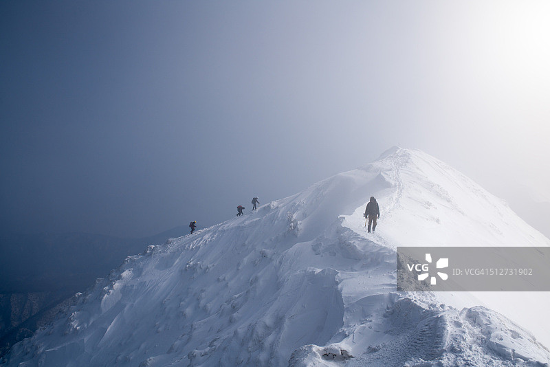 四名攀冰者攀登山顶图片素材