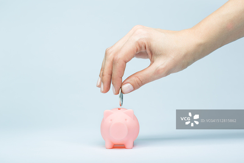 女人手往储蓄罐里放硬币图片素材