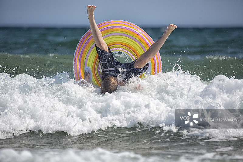 男孩在水上轮胎上冲浪图片素材