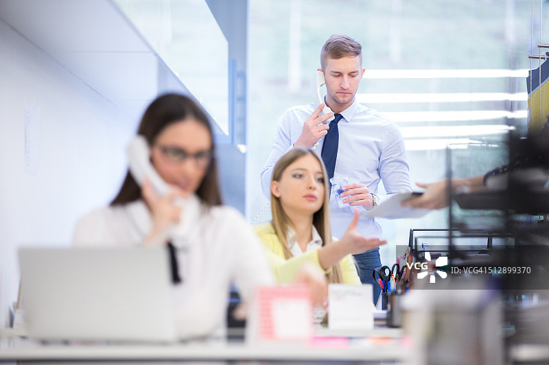 在办公室的办公桌旁使用手机的商人图片素材