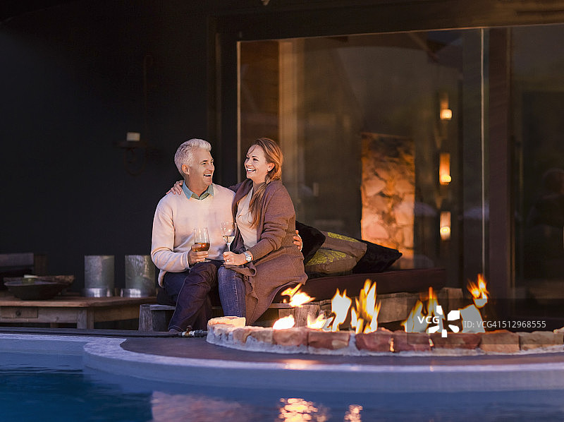 情侣夜晚坐在泳池边的火炉旁图片素材