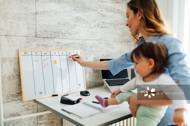 母亲在家工作，抱着她的宝宝图片素材