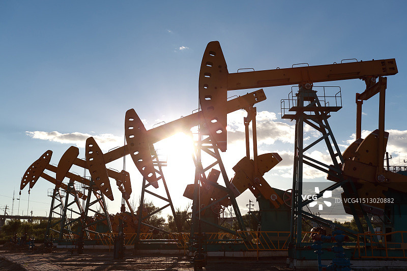 日落逆光下的金黄色石油钻机能源工业设备图片素材