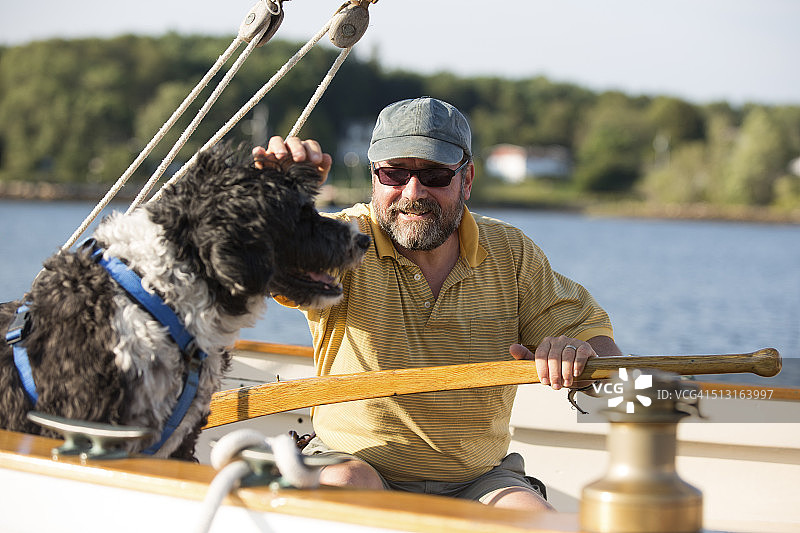 男子和他的狗在帆船上图片素材