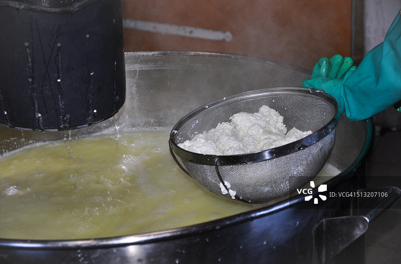 制作山羊奶酪时从沸腾的锅中取出凝乳图片素材