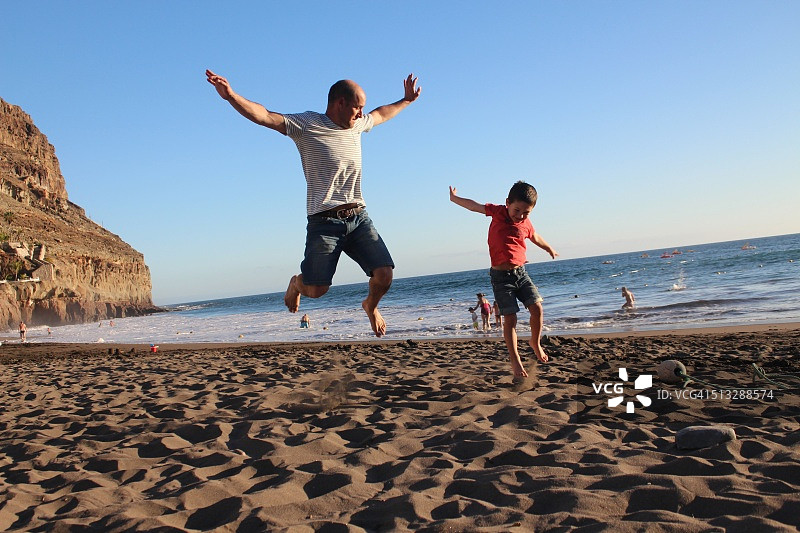 父子在沙滩上跳跃图片素材
