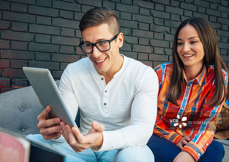 情侣坐在咖啡馆里，在平板电脑上使用社交媒体图片素材