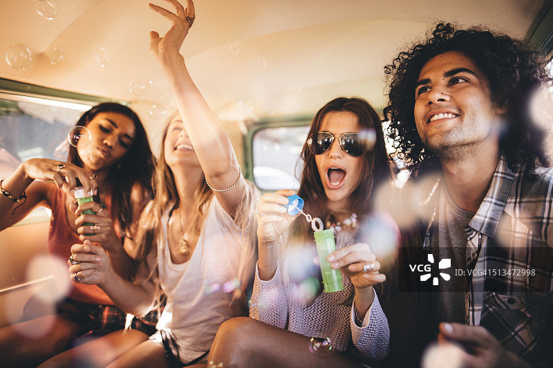 嬉皮士朋友们在复古面包车里举行泡泡派对图片素材