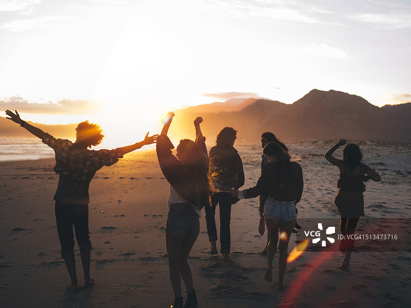 日落时分在海滩上跳舞的青少年朋友图片素材