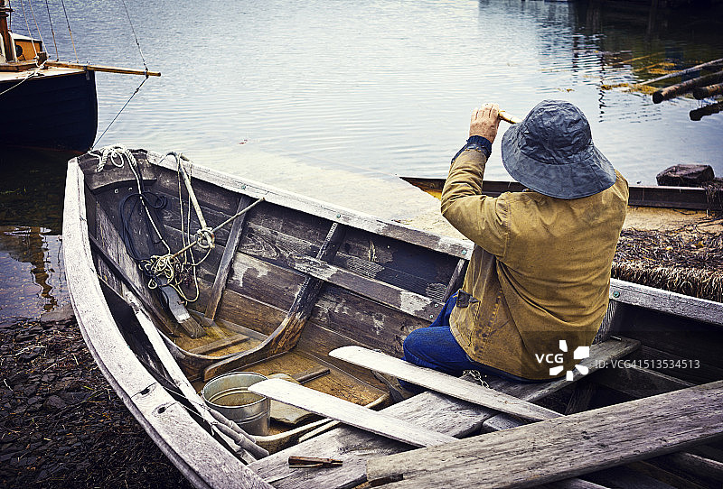 坐在多里船上拿着望远镜的渔民，新斯科舍省图片素材