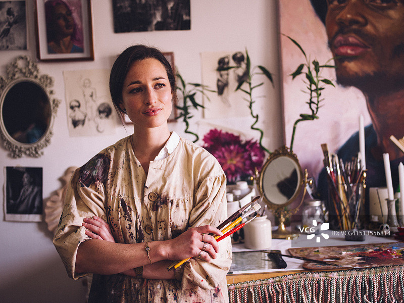 艺术家在工作室身穿沾满油漆的工作服，手持画笔图片素材