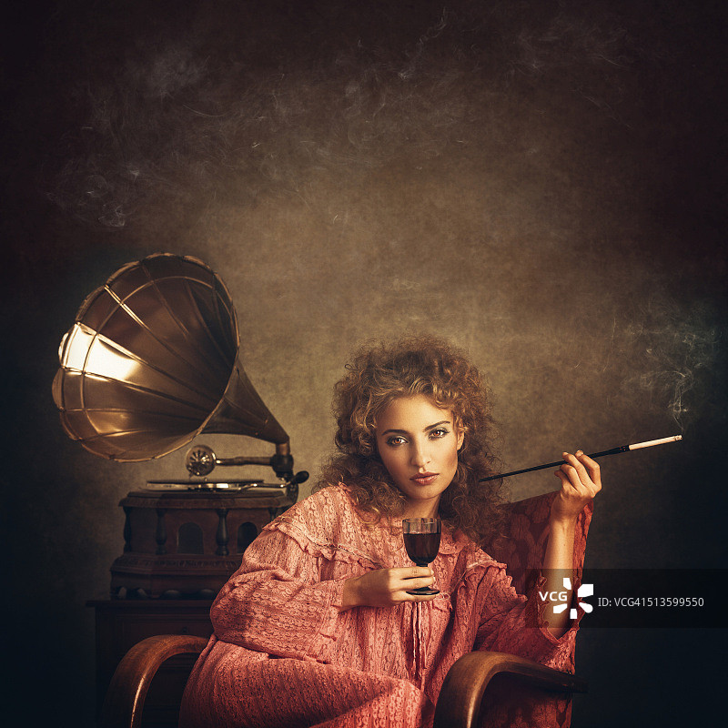 在老式唱机旁吸烟喝酒的复古女人图片素材